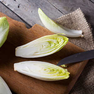 belgian endive on a wooden chopping board belgian endive on a wooden chopping board